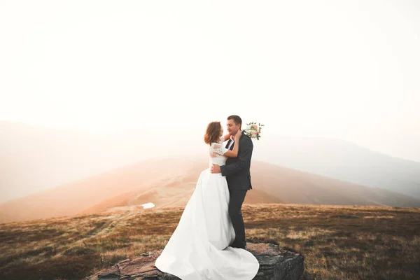 Jovem casal recém-casado, noiva e noivo beijando, abraçando na visão perfeita das montanhas, céu azul — Fotografia de Stock