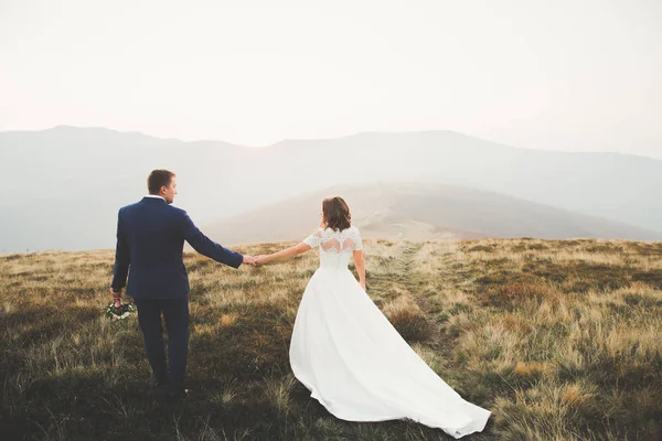 Hochzeitspaar posiert bei Sonnenuntergang am Hochzeitstag. Braut und Bräutigam verliebt — Stockfoto