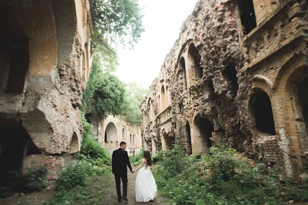 Juste mariés pose et embrasser avec une vieille forteresse sur le fond — Photo