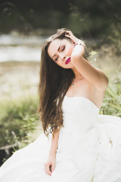Retrato de noiva deslumbrante com cabelos longos em pé junto ao rio — Fotografia de Stock