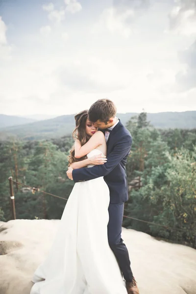 Hermosa pareja feliz boda joven posando sobre un fondo de acantilado de roca —  Fotos de Stock