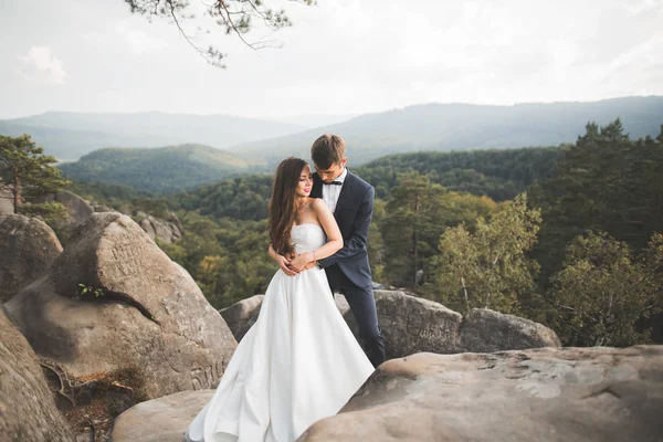 Casamento casal no amor beijando e abraçando perto de pedras na bela paisagem — Fotografia de Stock