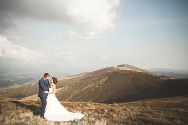 Hermosa pareja de boda besándose y abrazándose cerca de la montaña con vista perfecta —  Fotos de Stock