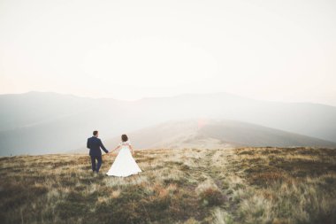 Bir dağın tepesinde günbatımında poz güzel düğün çifti