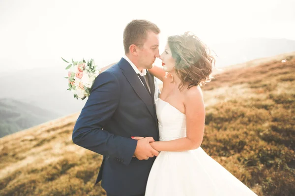 Jovem casal recém-casado, noiva e noivo beijando, abraçando na visão perfeita das montanhas, céu azul — Fotografia de Stock