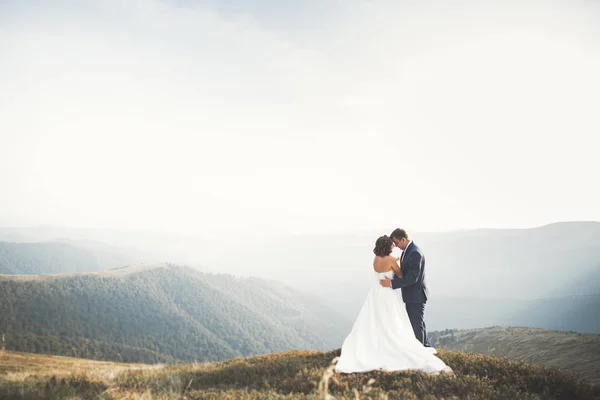 Šťastný svatební pár nevěsta a ženich na svatební den venku na horách skály. Šťastný manželský pár venku na přírodě, měkká slunečná světla — Stock fotografie
