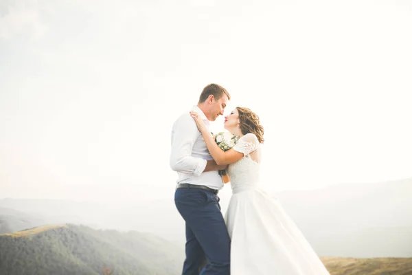 Hermosa pareja de boda besándose y abrazándose cerca de la montaña con vista perfecta —  Fotos de Stock