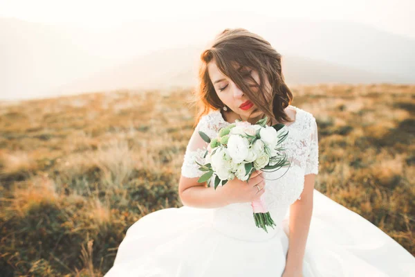 Bella sposa con un bouquet su sfondo di montagna al tramonto — Foto Stock