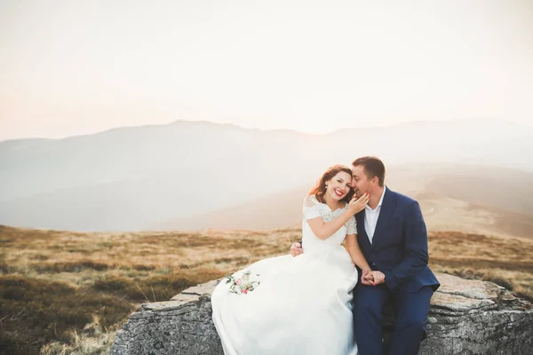 Bröllopsparet poserar på solnedgången vid bröllopsdag. Bruden och brudgummen i kärlek — Stockfoto