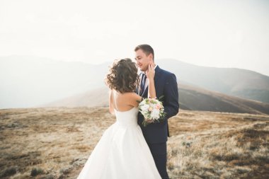 Bir dağın tepesinde günbatımında poz güzel düğün çifti