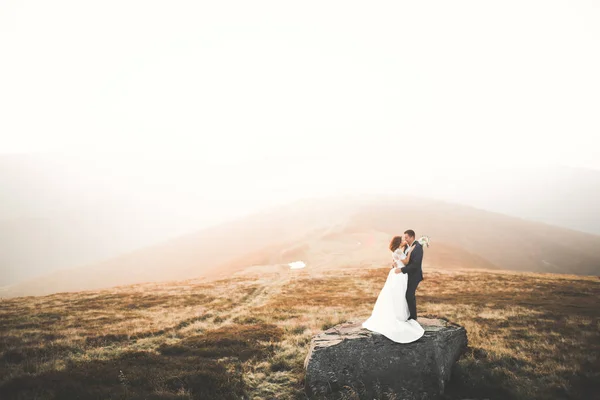 Fericit frumos cuplu de nunta mireasa si mire la ziua nuntii in aer liber pe stânca muntilor. Căsătorie fericită cuplu în aer liber pe natură, lumini moi însorite — Fotografie, imagine de stoc