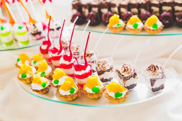 Delicious and tasty dessert table with cupcakes shots at reception closeup — Stock Photo, Image