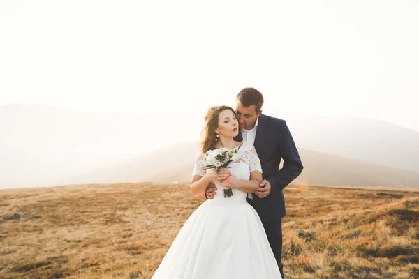 Beautiful wedding couple posing on top of a mountain at sunset — Stock Photo, Image