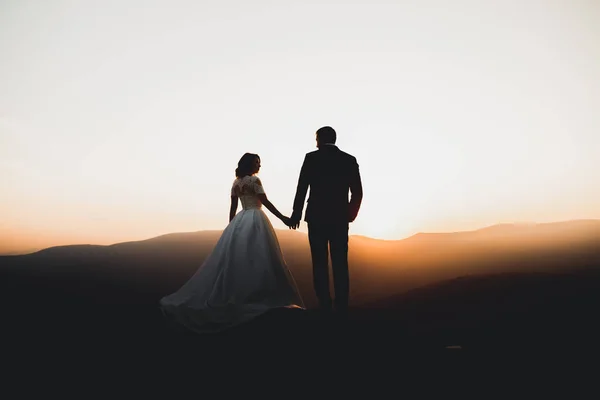 Felice bella coppia di sposi sposa e lo sposo il giorno del matrimonio all'aperto sulla roccia montagne. Felice matrimonio coppia all'aperto sulla natura, luci soffuse e soleggiate — Foto Stock