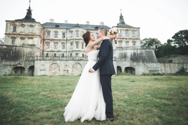 Novomanželům pózy a líbání s staré pevnosti na pozadí — Stock fotografie