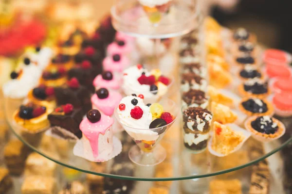 Délicieuse et savoureuse table à dessert avec des petits gâteaux plans à la réception gros plan — Photo
