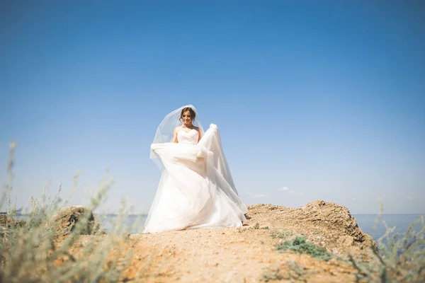 Bella sposa in abito da sposa bianco in posa vicino al mare con bellissimo sfondo — Foto Stock