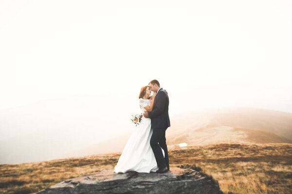 Happy beautiful wedding couple bride and groom at wedding day outdoors on the mountains rock. Happy marriage couple outdoors on nature, soft sunny lights.