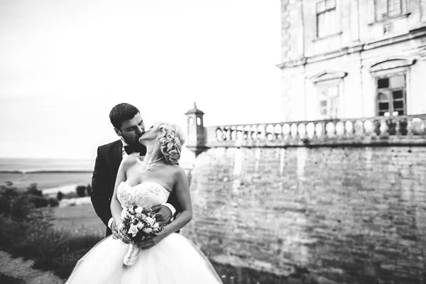 Hermosa boda romántica pareja de recién casados abrazos cerca del viejo castillo —  Fotos de Stock