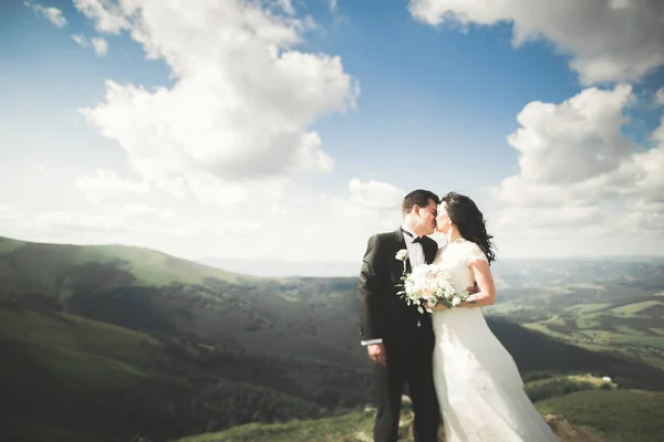 Jovem casal recém-casado, noiva e noivo beijando, abraçando na visão perfeita das montanhas, céu azul — Fotografia de Stock