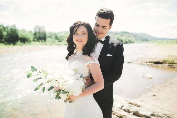 Elegante zachte stijlvolle bruid en bruidegom in de buurt van rivier met stenen. Bruidspaar in liefde — Stockfoto