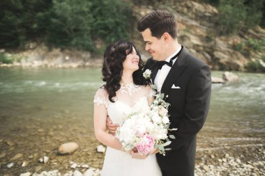 Zarif nazik şık damat ve gelin taşlarla Nehri yakınında. Evlilik çift aşık