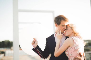 Çatıda mükemmel şehir manzaralı elele ve sarılma poz aşık genç bir çift. Güzel gün batımı