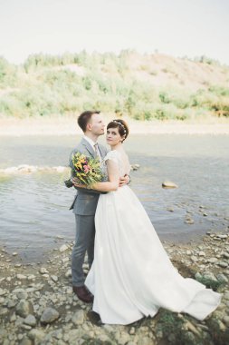 Zarif nazik şık damat ve gelin taşlarla Nehri yakınında. Evlilik çift aşık