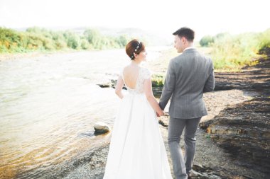 Zarif nazik şık damat ve gelin taşlarla Nehri yakınında. Evlilik çift aşık