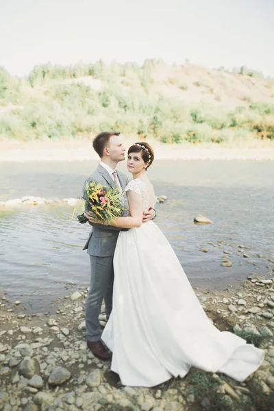 Zarif nazik şık damat ve gelin taşlarla Nehri yakınında. Evlilik çift aşık