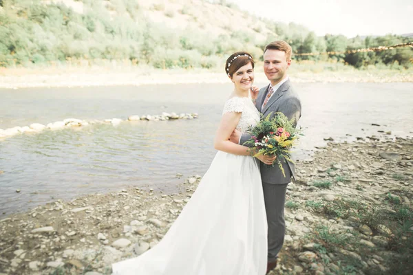 Gelin ve damat güzel düğün buket tutarak. Nehir kenarında poz