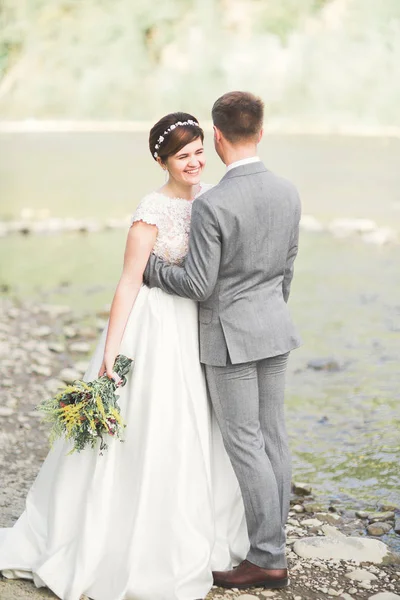 ハンサムなロマンチックな新郎と風光明媚な山の中の川に近いポーズ美しい花嫁 — ストック写真