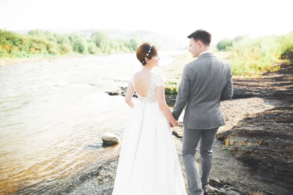 Zarif nazik şık damat ve gelin taşlarla Nehri yakınında. Evlilik çift aşık