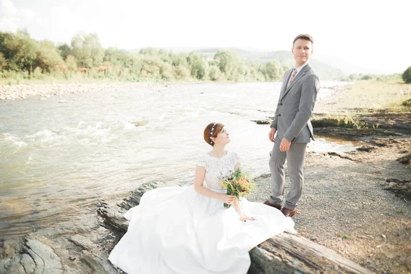 Mariée et marié tenant beau bouquet de mariage. Poser près de la rivière — Photo