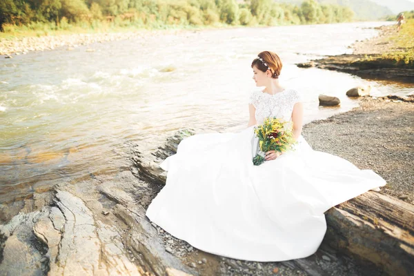 Senhora bonita, noiva em um vestido de noiva posando perto do rio — Fotografia de Stock