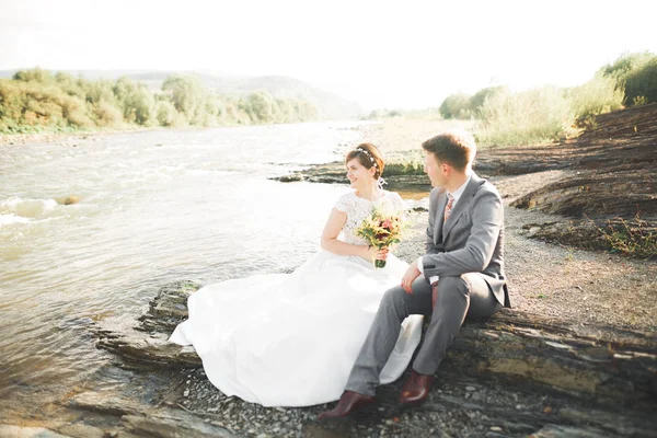 Yakışıklı romantik damat ve güzel gelin Nehri manzaralı dağlarında yakınında poz