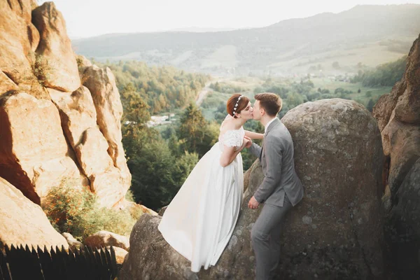 Hermosa novia y elegante novio caminando en el paisaje soleado, pareja de bodas, montañas de ceremonia de lujo con una vista increíble, espacio para el texto — Foto de Stock