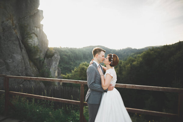 Kissing wedding couple staying over beautiful landscape.