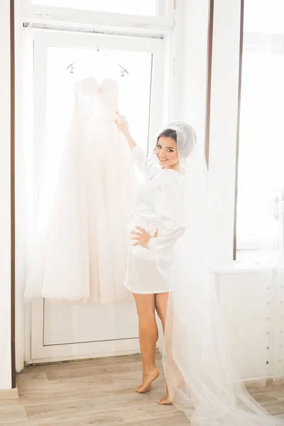 Gorgeous bride in robe posing and preparing for the wedding ceremony face in a room — Stock Photo, Image