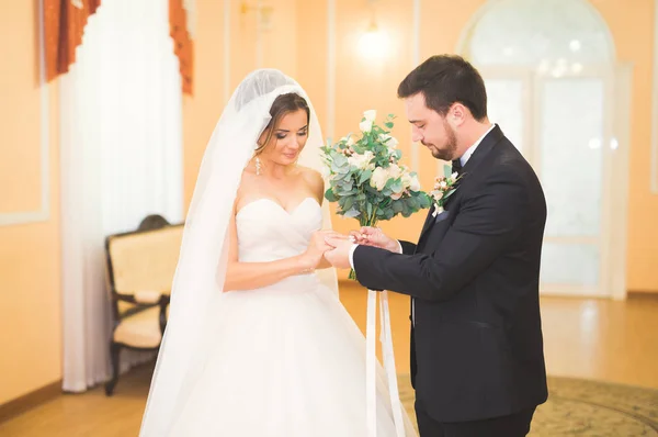 Schoonheid bruid en knappe bruidegom dragen ringen elkaar. Bruidspaar op de huwelijksceremonie. — Stockfoto