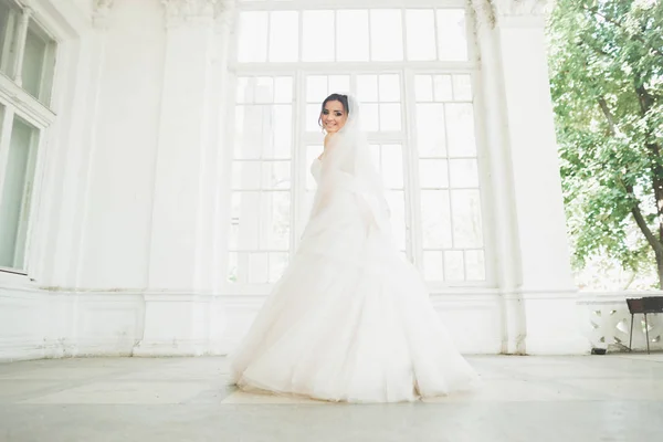 Krásná nevěsta ve svatebních šatech s dlouhou sukní, bílým pozadím, tancovat a smát — Stock fotografie