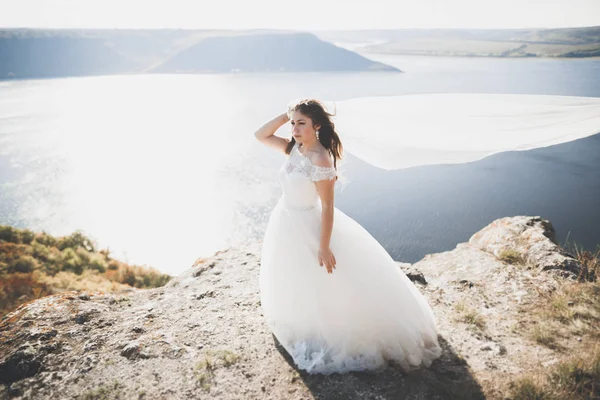 Bella signora, sposa in posa in un abito da sposa vicino al mare al tramonto — Foto Stock