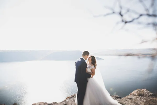 Hochzeitspaar küsst und umarmt sich auf Felsen nahe blauem Meer — Stockfoto