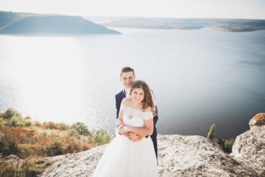 Şık, şık, mutlu bir düğün çifti, gelin, deniz ve gökyüzünün arka planında muhteşem bir damat.