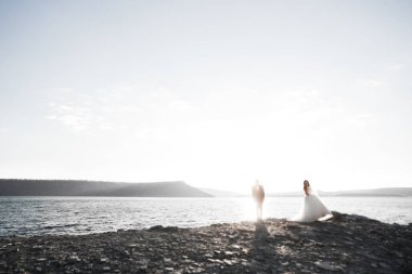 Şık, şık, mutlu bir düğün çifti, gelin, deniz ve gökyüzünün arka planında muhteşem bir damat.