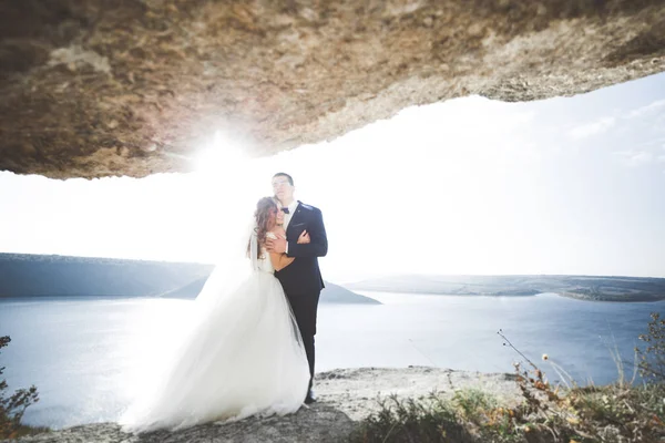 Şık, şık, mutlu bir düğün çifti, gelin, deniz ve gökyüzünün arka planında muhteşem bir damat.