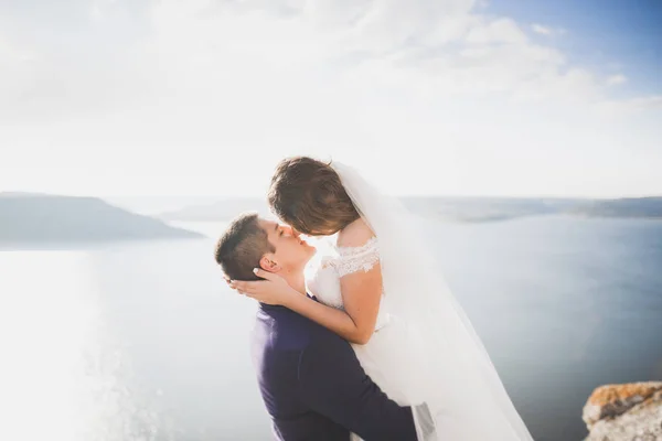 Bryllupspar kysser og klemmer på stein nær blått hav – stockfoto