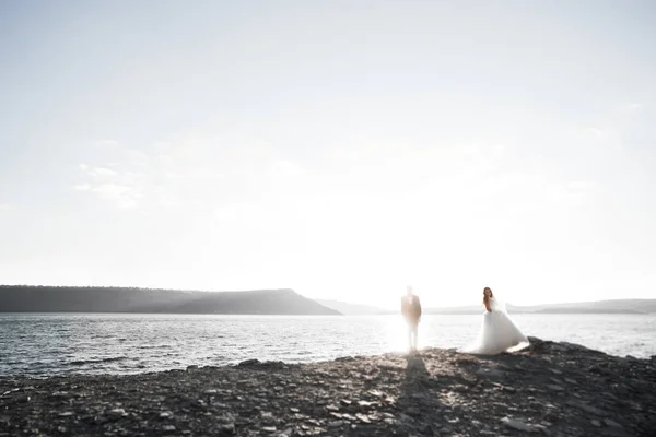 Elegante pareja de boda feliz elegante, novia, magnífico novio en el fondo del mar y el cielo —  Fotos de Stock