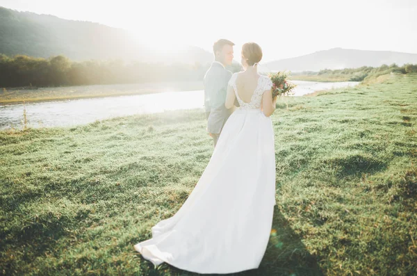 Hermosa novia y elegante novio caminando en el paisaje soleado, pareja de bodas, montañas de ceremonia de lujo con una vista increíble, espacio para el texto — Foto de Stock