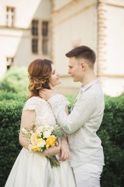 Güzel, romantik bir düğün. Yeni evliler. Eski kalenin yakınlarında sarılıyorlar.